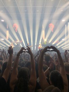 a group of people holding their hands up in the air at a concert with bright lights