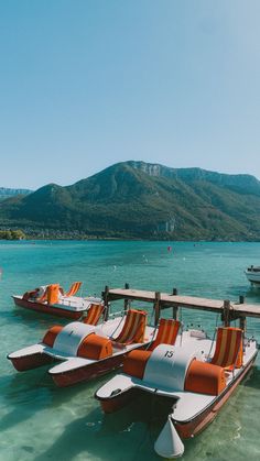 there are many boats that are tied to the dock in the water and one is orange