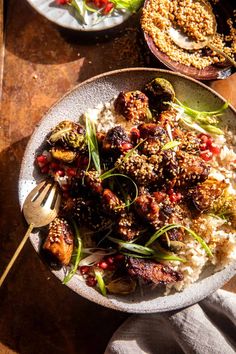 a bowl filled with rice and vegetables on top of a wooden table next to other dishes