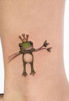 a small frog with a crown on its head is sitting on the back of a woman's leg