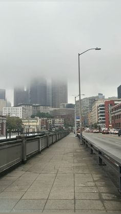 the city skyline is covered in fog and smoggy clouds as seen from an overpass