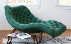 a green chair sitting on top of a wooden floor next to a white and black rug