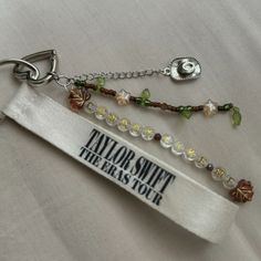 a keychain with some beads and charms attached to it's side that says taylor smith the arts tour