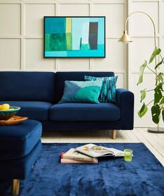 a blue couch and ottoman in a living room with a large painting on the wall