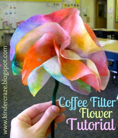 a person holding up a flower made out of coffee filter paper with the words coffee filter on it