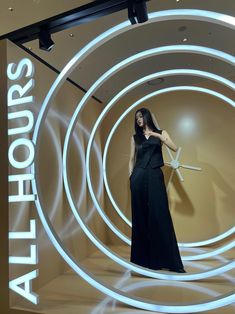 a woman is standing in front of a display with white lights and circular rings on it