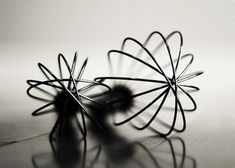 two wire sculptures sitting on top of a table next to each other in black and white