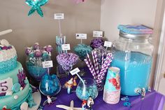 the table is set up for a little mermaid themed birthday party with candy and decorations