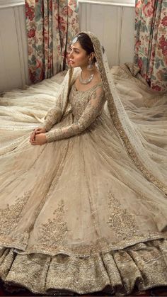 a woman sitting on top of a bed wearing a wedding dress with long sleeves and a veil