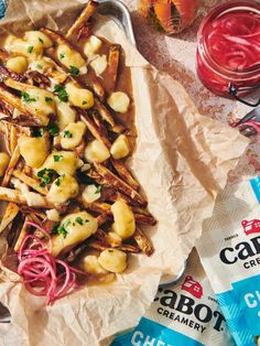 some food that is sitting on top of wax paper and next to two bags of chips