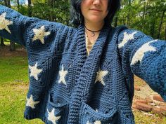 a woman wearing a blue crocheted sweater with white stars on it and her arms stretched out