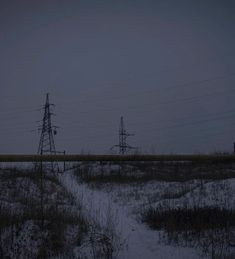 an empty field at night with power lines in the distance and snow on the ground