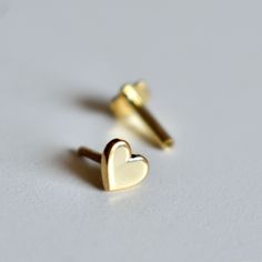 "Sweet little solid gold Heart stud, handcrafted in 14k gold, this pin is available in a variety of closure options for different types of piercings. A cute stud for all ages! * Gold - 14K Solid Gold * 4mm*4mm * Standard length of the post below design is 6-7mm. It can be adjusted as per requirements as well. DIAMOND NOSE PIN : https://www.etsy.com/listing/267480507/ ROUGH EMERALD NOSE STUD : https://www.etsy.com/listing/267480037/ If you like this pin, please press \"Pin it\" button on the righ Dainty Tiny Gold Heart Earrings, Tiny 14k Gold Cartilage Earrings For Anniversary, Dainty 14k Gold Cartilage Earrings For Gift, Dainty 14k Gold Cartilage Earrings As Gift, Tiny Dainty Yellow Gold Heart Earrings, Dainty Tiny Yellow Gold Heart Earrings, Heart-shaped Internally Threaded Cartilage Earrings As Gift, Tiny Gold Cartilage Earrings As Gift, Tiny Gold Cartilage Earrings For Gift