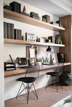 two black chairs sitting on top of a wooden shelf next to a white rug and bookshelf