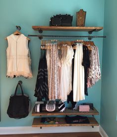 a closet with clothes and handbags hanging on the rack, next to a purse