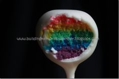 a close up of a cake on a spoon with multicolored frosting and sprinkles