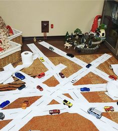 toy cars are scattered on the floor in front of a basket full of other toys