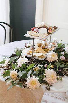 an arrangement of food on a table with flowers and greenery around the edges is displayed