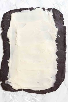 an uncooked black and white cake with icing on it's edges