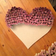 a heart made out of wine corks sitting on top of a wooden table