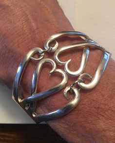 a person wearing a silver bracelet with an omen symbol on it's wrist