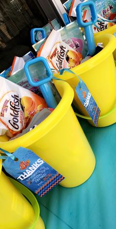 three yellow buckets filled with snacks sitting on top of a blue table