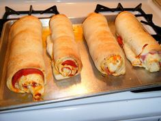 four wrapped sandwiches sitting on top of a stove