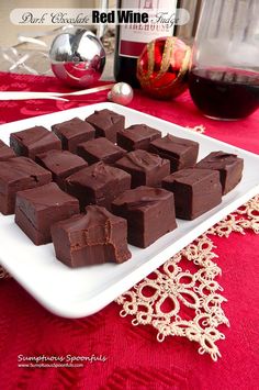 a white plate topped with chocolate pieces next to a glass of wine and a bottle of red wine