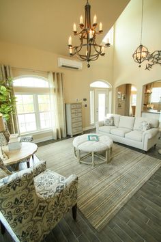 a living room filled with furniture and a chandelier hanging over the top of it