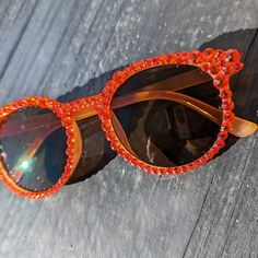 Material of glasses: Plastic Frame Color: Beige Frame Shape: Round Lens Color: Tan Crystal Color: Orange Flame Note: These are fashion glasses. Not intended to protect eyes against strong sunlight.  ✨Every stone is placed by hand and each pair is one of a kind. Individually adorned with dazzling rhinestones, these sunglasses create a radiant sparkle that catches every eye. ✨ 💕Every pair comes with a microfiber pouch to keep your shades safe and can be used for a quick, easy cleaning.💕 ✨Shipping: Usually ships next day but allow up to 2 days. 💕 ✨Returns: We accept returns up to 14 days from purchase. Please reach out to us and let us know if you are unhappy with your purchase. We want everyone to shimmer and shine and will work with you to make that happen!✨ Looking for something specifi Party Sunglasses With Orange Gradient Lenses, Party Sunglasses With Tinted Round Lenses, Round Tinted Sunglasses For Party, Round Tinted Lens Sunglasses For Parties, Round Tinted Sunglasses For Parties, Adjustable Clear Sunglasses For Parties, Orange Sunglasses, Handmade Sunglasses, Shimmer And Shine