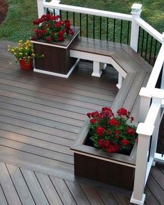 two planters with red flowers are sitting on a wooden deck next to a white railing