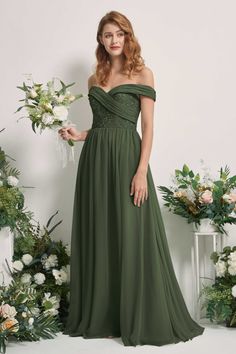 a woman in a long green dress standing next to flowers