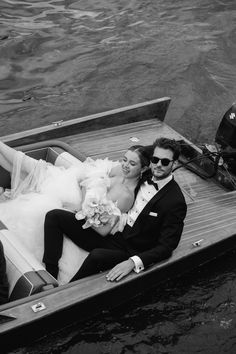 a bride and groom in a boat on the water