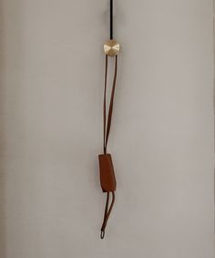 a clock hanging from the side of a wall next to a brown leather purse on a hook