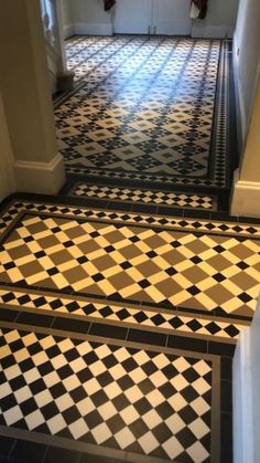 a hallway with black and white checkered flooring on the side of the stairs