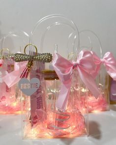 several small bottles with pink bows and lights in them on a white tableclothed surface