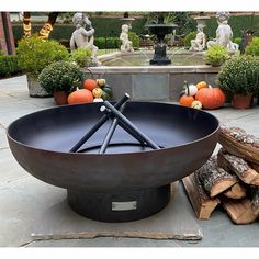 an outdoor fire pit with logs and pumpkins in the background