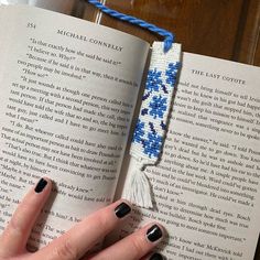 a woman's hand holding an open book with blue and white flowers on it