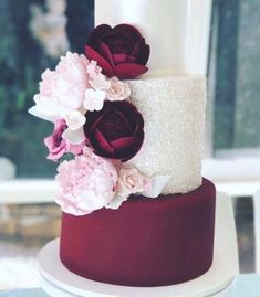 a white and red wedding cake with flowers on top