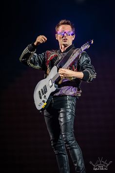 a man in leather pants holding a guitar