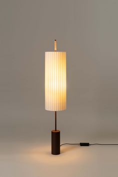 a lamp that is sitting on top of a wooden stand with a white shade over it