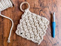 a crochet pot holder with yarn next to it on a wooden table,