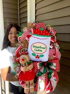 a woman holding a christmas wreath with gingerbread cookies and candy canes on it