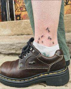 a person's foot with small black bugs on the shoe and white socks behind them