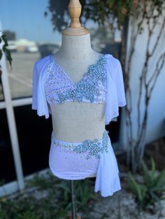 a white top with blue sequins on it sitting on a mannequin