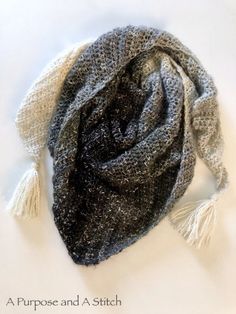 a black and white scarf with tassels laying on top of a table next to a cup