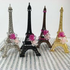 three miniature eiffel tower made out of plastic beads and flowers on a table