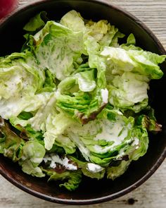 a bowl filled with lettuce on top of a wooden table