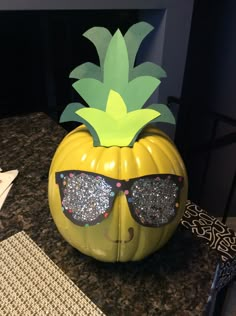 a yellow pumpkin with sunglasses on it's head and a pineapple cut out of the top