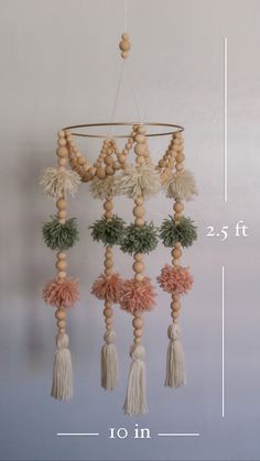 a wooden beaded mobile with tassels and pom - poms hanging from it